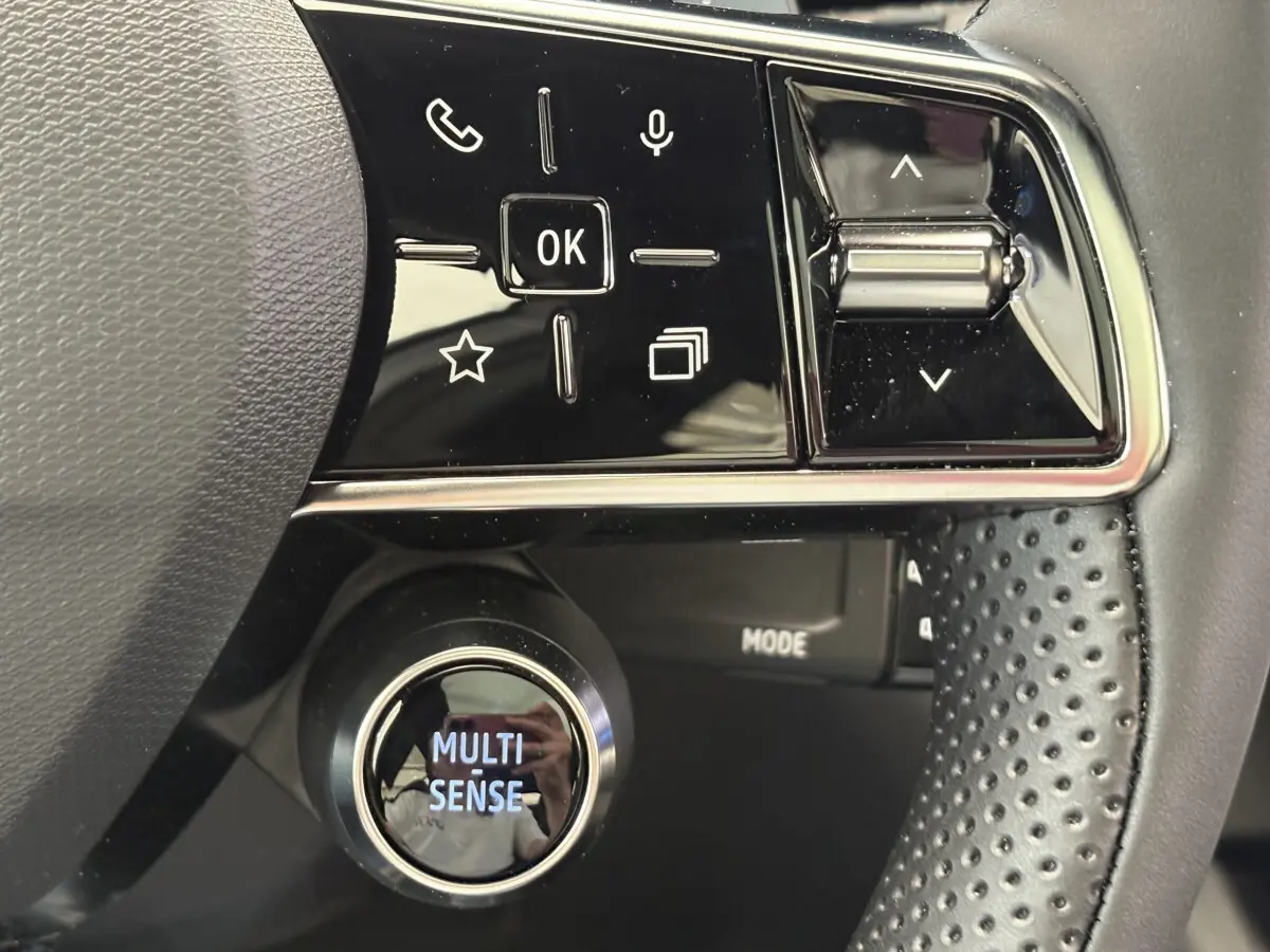 Gros plan sur le volant cuir noir du Renault Austral 2025 avec commandes multifonctions et bouton Multi-Sense lumineux.