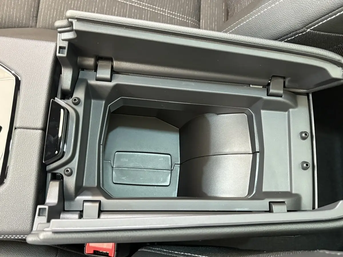 Vue rapprochée de la console centrale ouverte du Renault Austral Techno blanc, montrant le rangement intérieur noir.