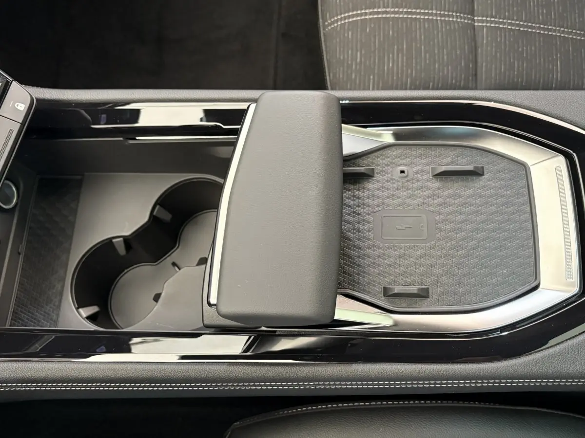 Vue plongeante sur la console centrale noire du Renault Austral 2025 avec accoudoir et emplacement de recharge sans fil.