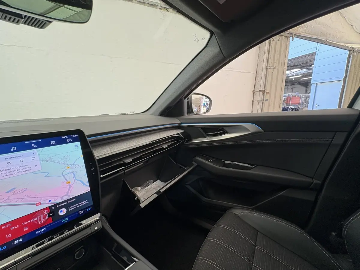 Intérieur côté passager du Renault Austral blanc 2025, tableau de bord moderne avec écran tactile et boîte à gants ouverte.