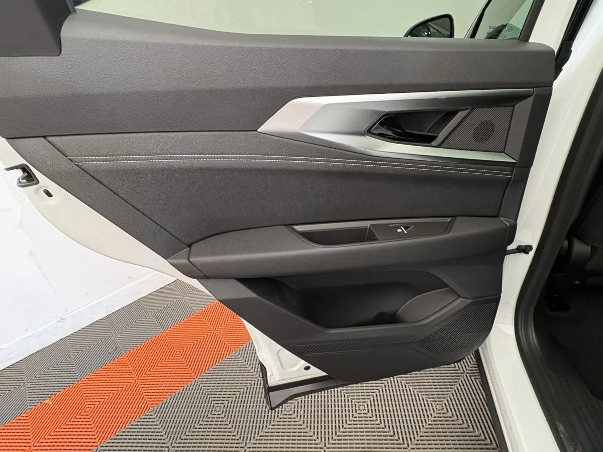Gros plan sur la porte arrière gauche blanche du Renault Austral 2025, avec garniture noire et détails métalliques.