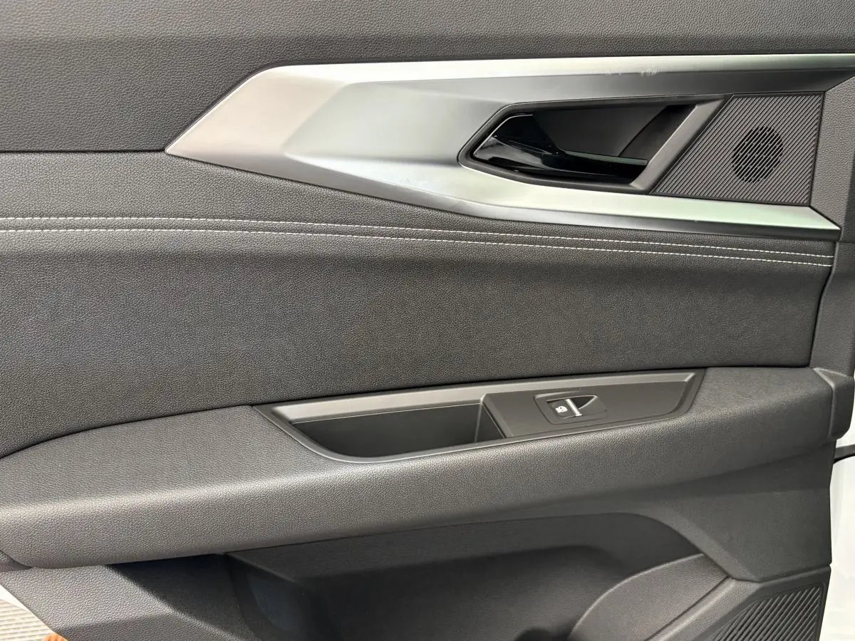 Gros plan sur la porte intérieure côté droit du Renault Austral blanc, avec poignée argentée et bouton de fenêtre.