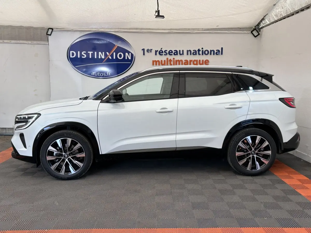 Profil côté gauche d'un Renault Austral blanc 2025 avec jantes alliage et toit noir en showroom.