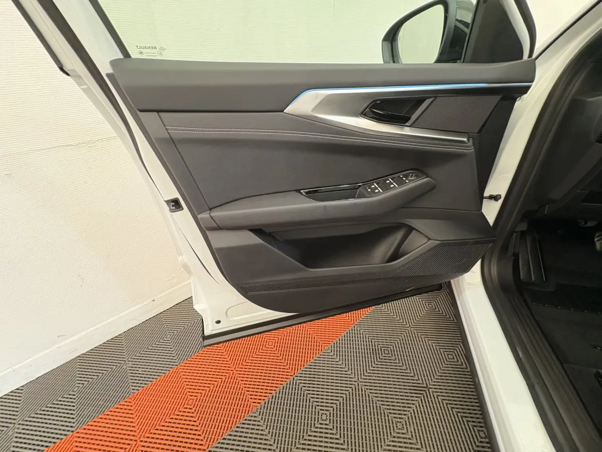 Vue intérieure de la porte avant gauche du Renault Austral blanc 2025 avec garniture noire et commandes électriques.
