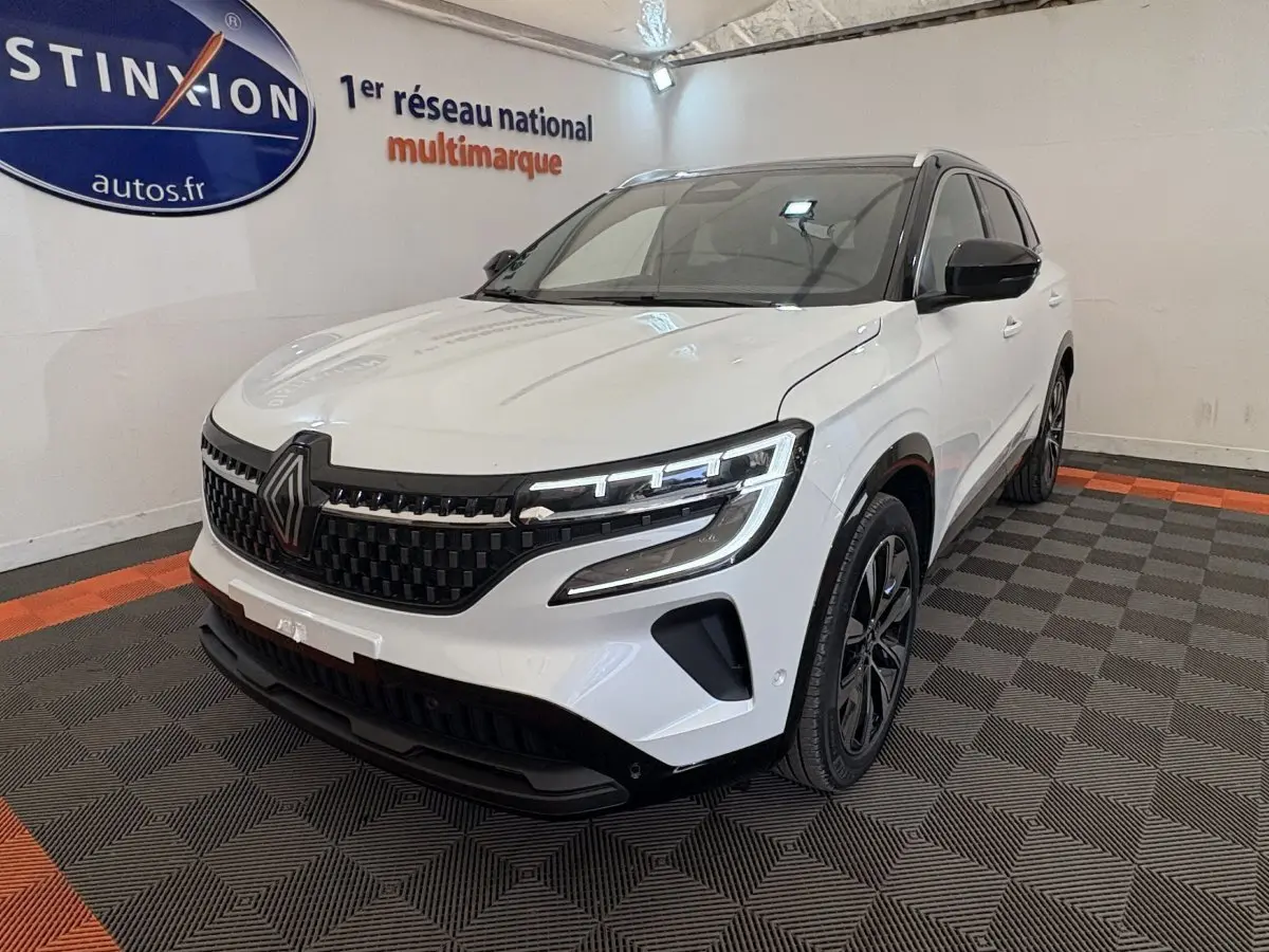 Renault Austral blanc en 3/4 avant droit, avec calandre noire à damier et phares LED distinctifs.
