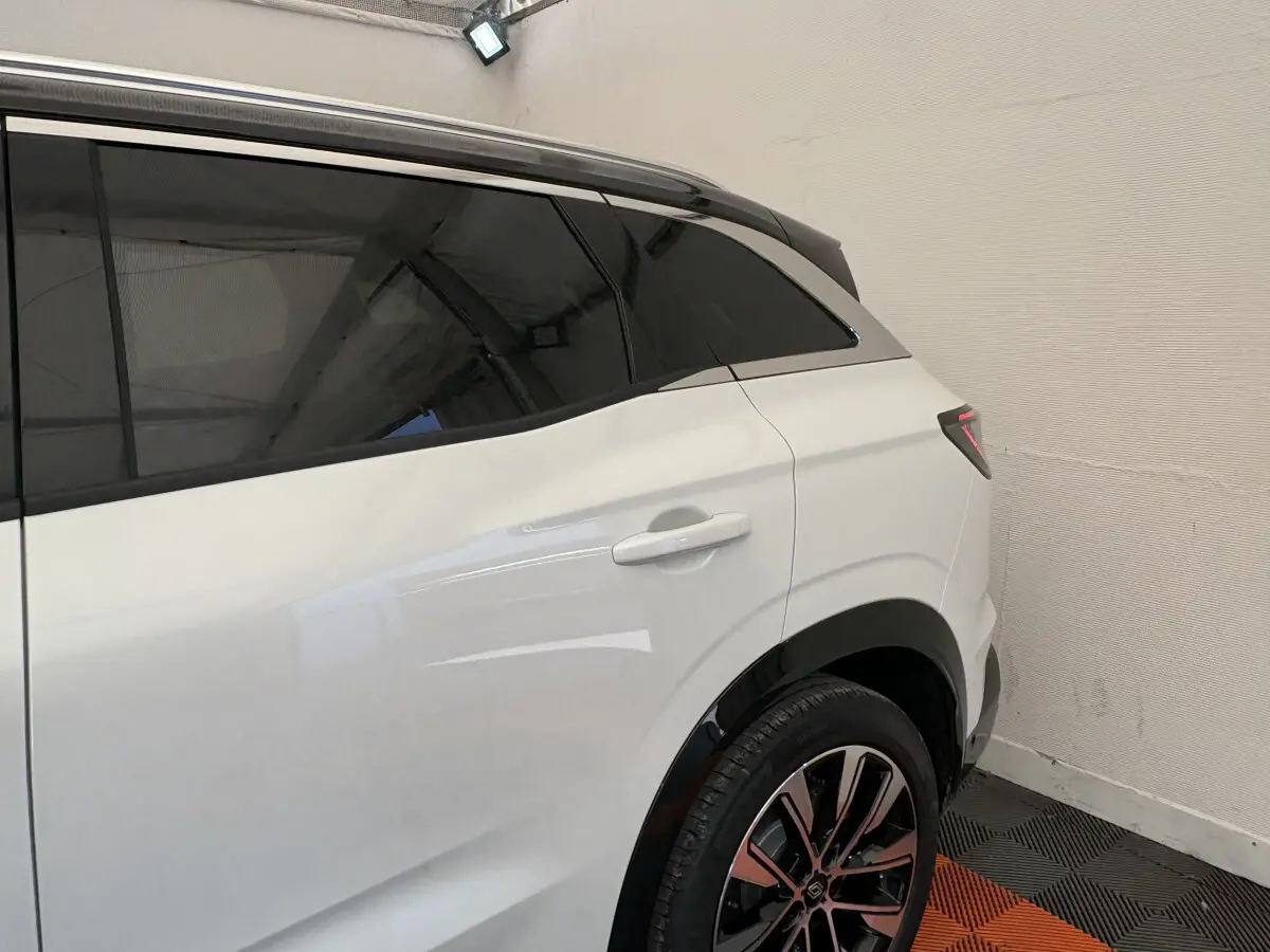 Vue latérale arrière droite du Renault Austral blanc avec vitres teintées et jantes alliage distinctives.