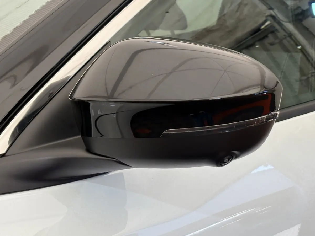 Rétroviseur côté gauche noir brillant avec caméra intégrée sur Renault Austral blanc, vue rapprochée du côté conducteur.