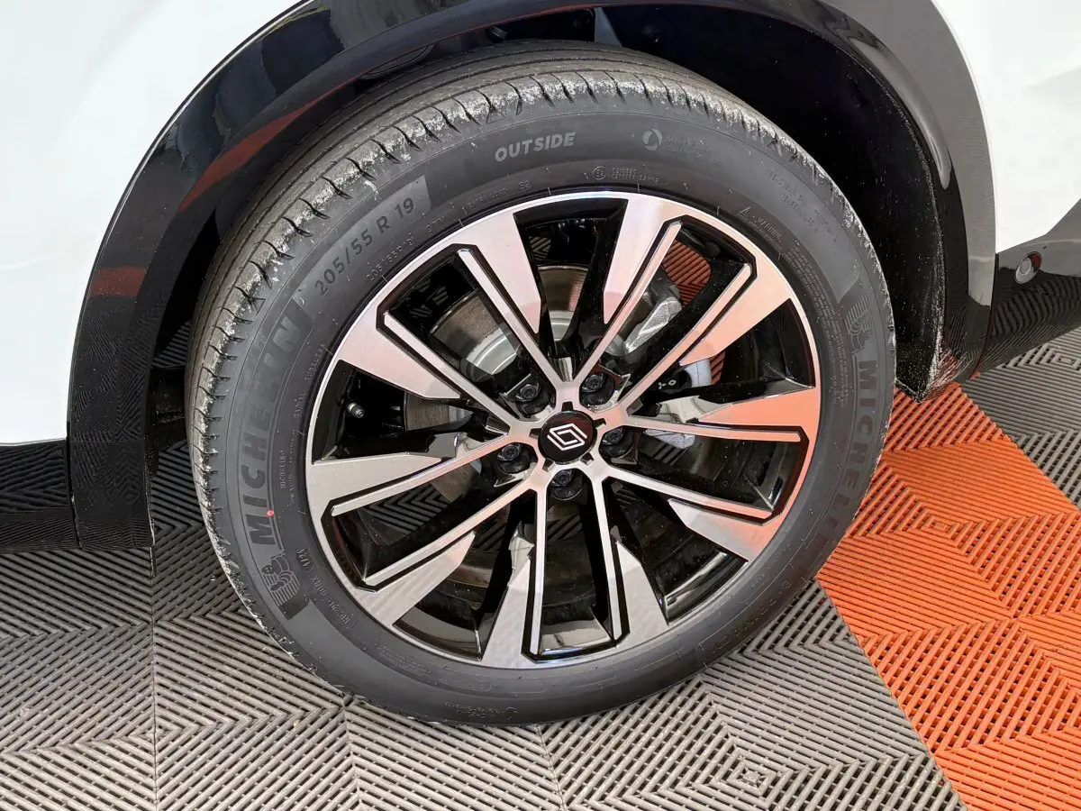 Gros plan sur la roue avant droite du Renault Austral blanc, avec jante alliage noire et argentée au design moderne.