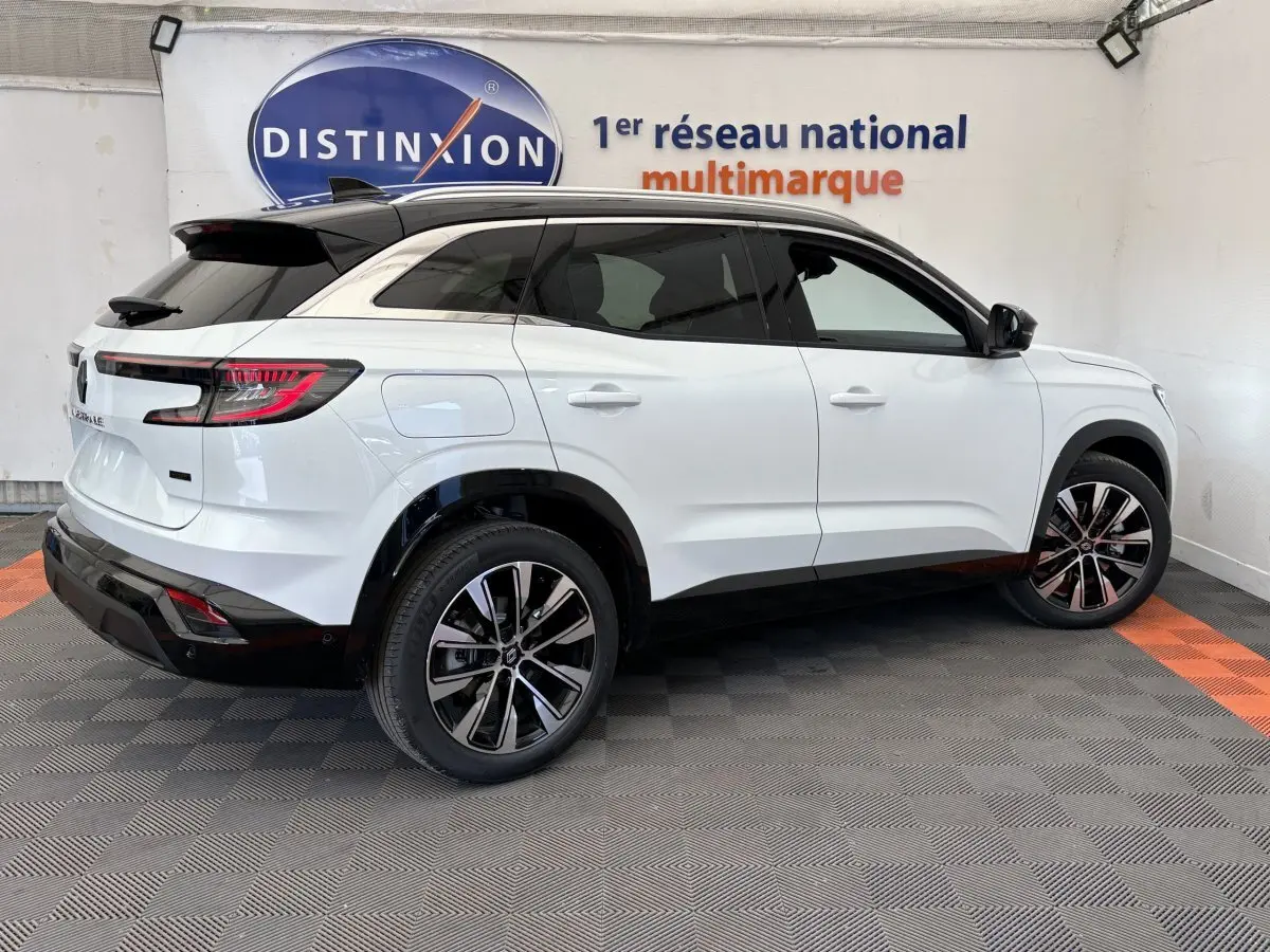 Vue latérale droite d'un Renault Austral blanc 2025 avec toit noir et jantes alliage modernes dans un showroom.