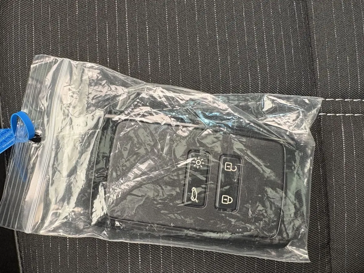 Télécommande noire Renault Austral Techno hybride dans un sachet plastique sur tissu gris à coutures blanches.