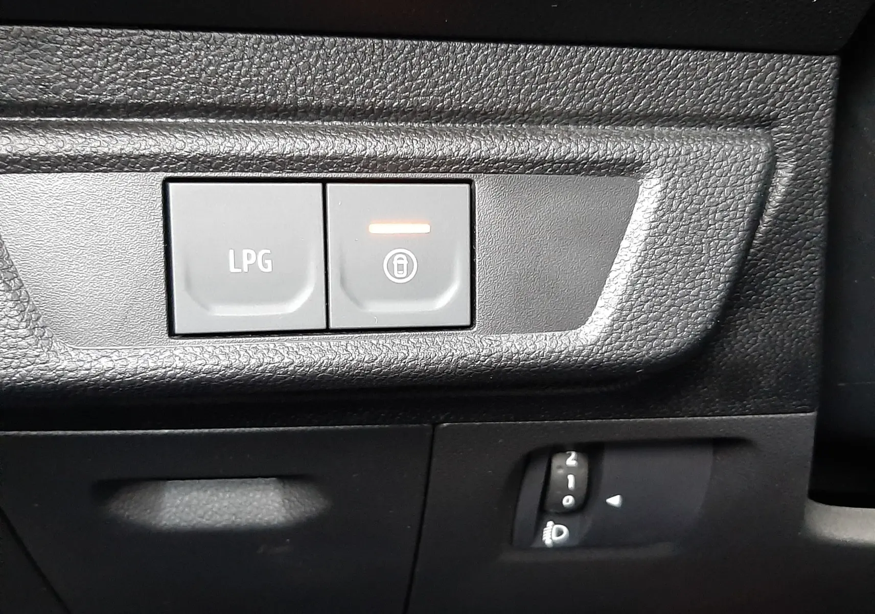 Gros plan sur les boutons de commande LPG et verrouillage, tableau de bord noir du Dacia Jogger 2025 côté gauche.