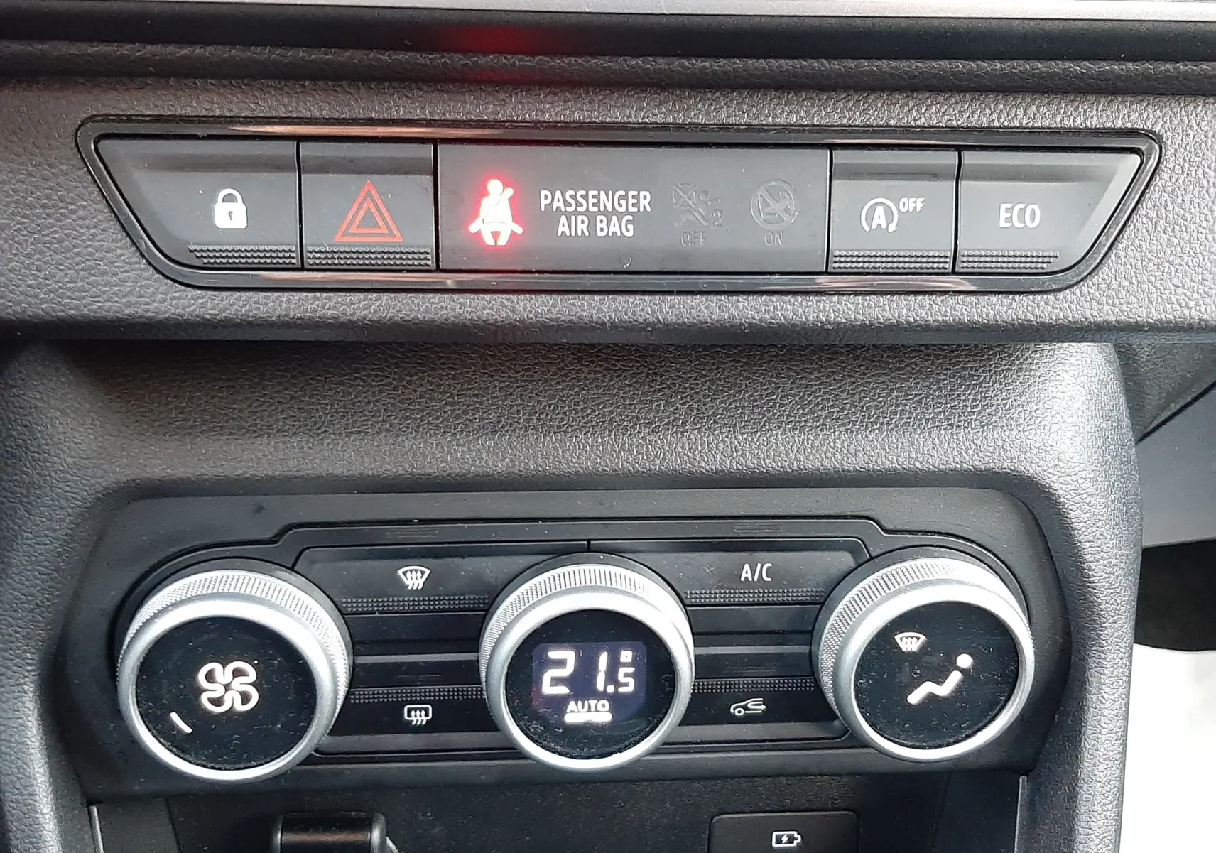 Vue rapprochée du tableau de bord du Dacia Jogger 2025, montrant les commandes de climatisation et les voyants de sécurité allumés.