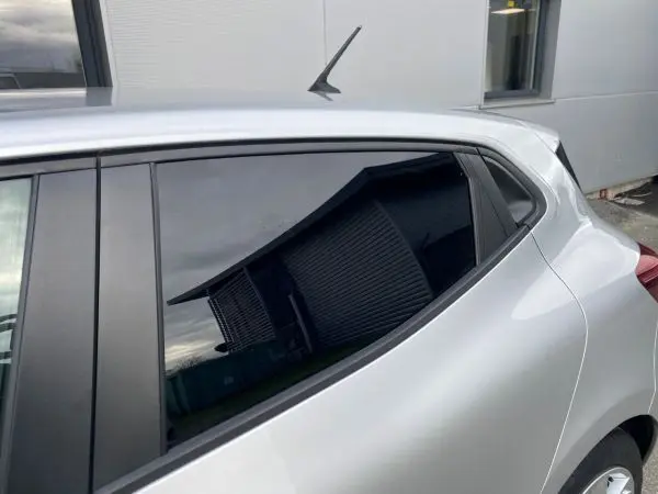 Vue rapprochée du côté arrière droit de la Renault Clio V gris platine, mettant en valeur la ligne de toit et la vitre teintée.