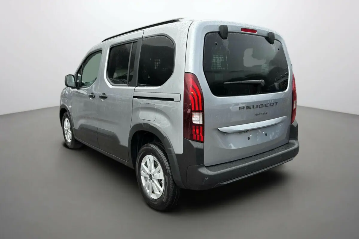 Vue 3/4 arrière droit du Peugeot Rifter gris Artense avec vitres surteintées et grille de séparation visible dans le coffre.