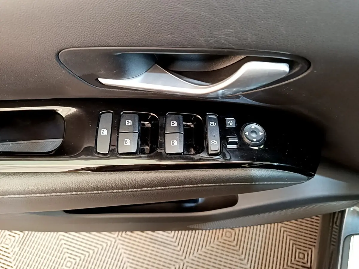 Gros plan sur la commande des vitres et rétroviseurs côté conducteur d’un Hyundai Tucson gris foncé 2022.