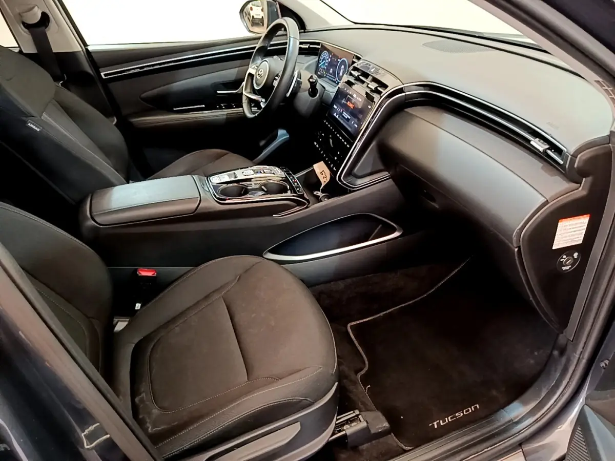 Vue intérieure côté passager du Hyundai Tucson 1.6 Hybrid 230 Creative 2022 avec sièges noirs et tableau de bord moderne.