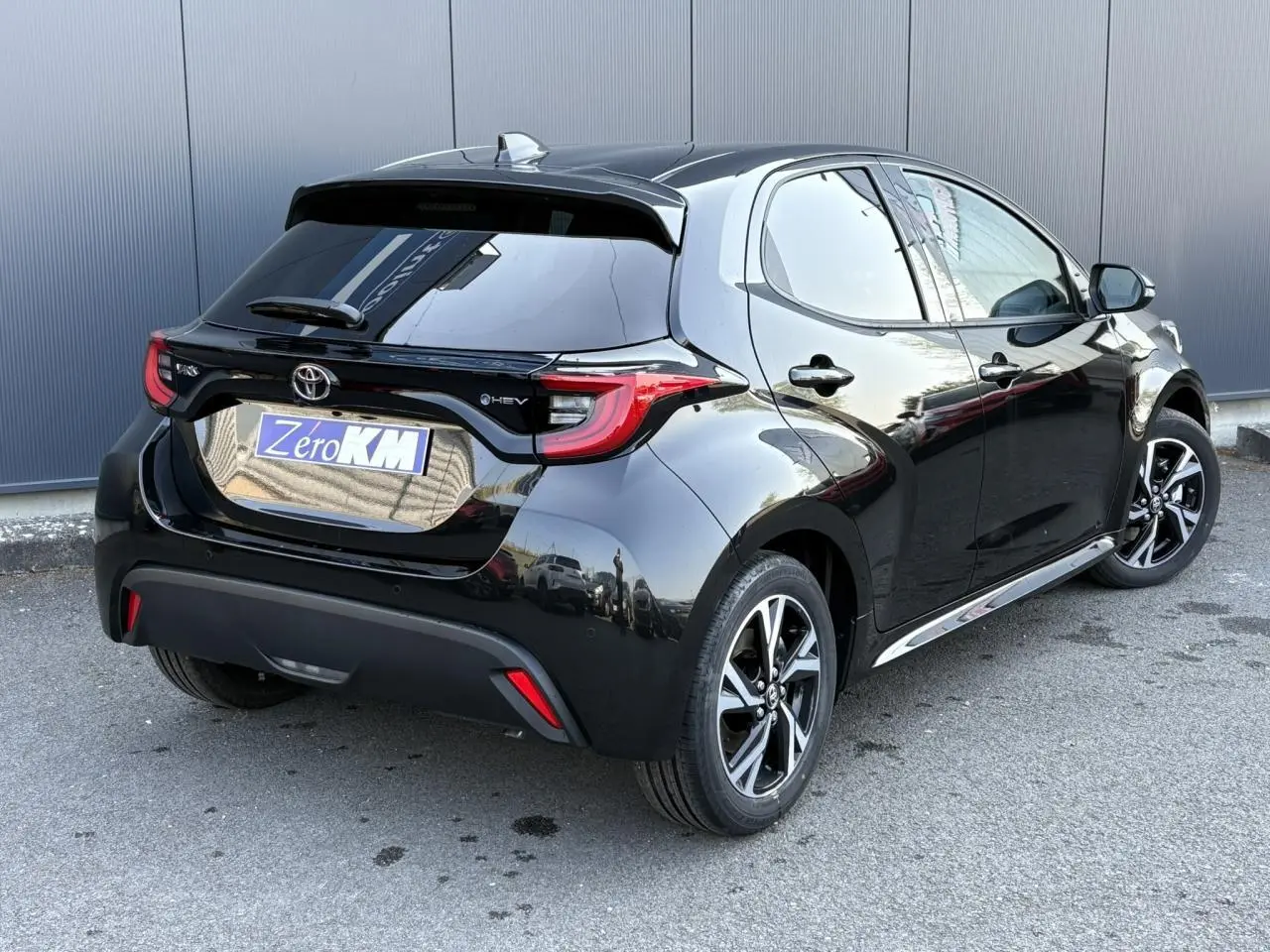 Toyota Yaris Hybride noire vue en 3/4 arrière droit, avec jantes alliage et feux arrière LED distinctifs.