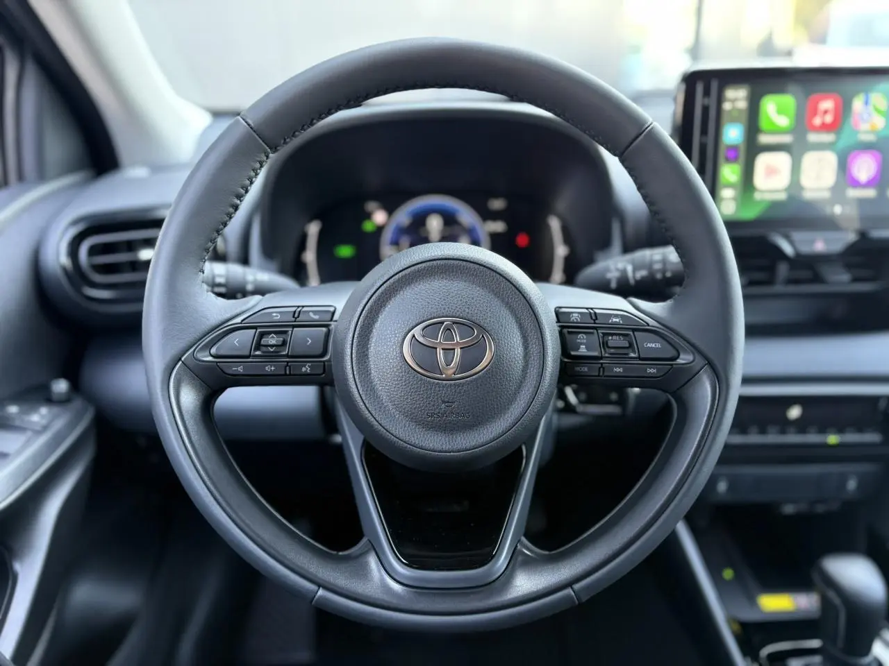Volant cuir noir de la Toyota Yaris Hybride 2025 avec commandes intégrées et écran tactile multimédia en arrière-plan