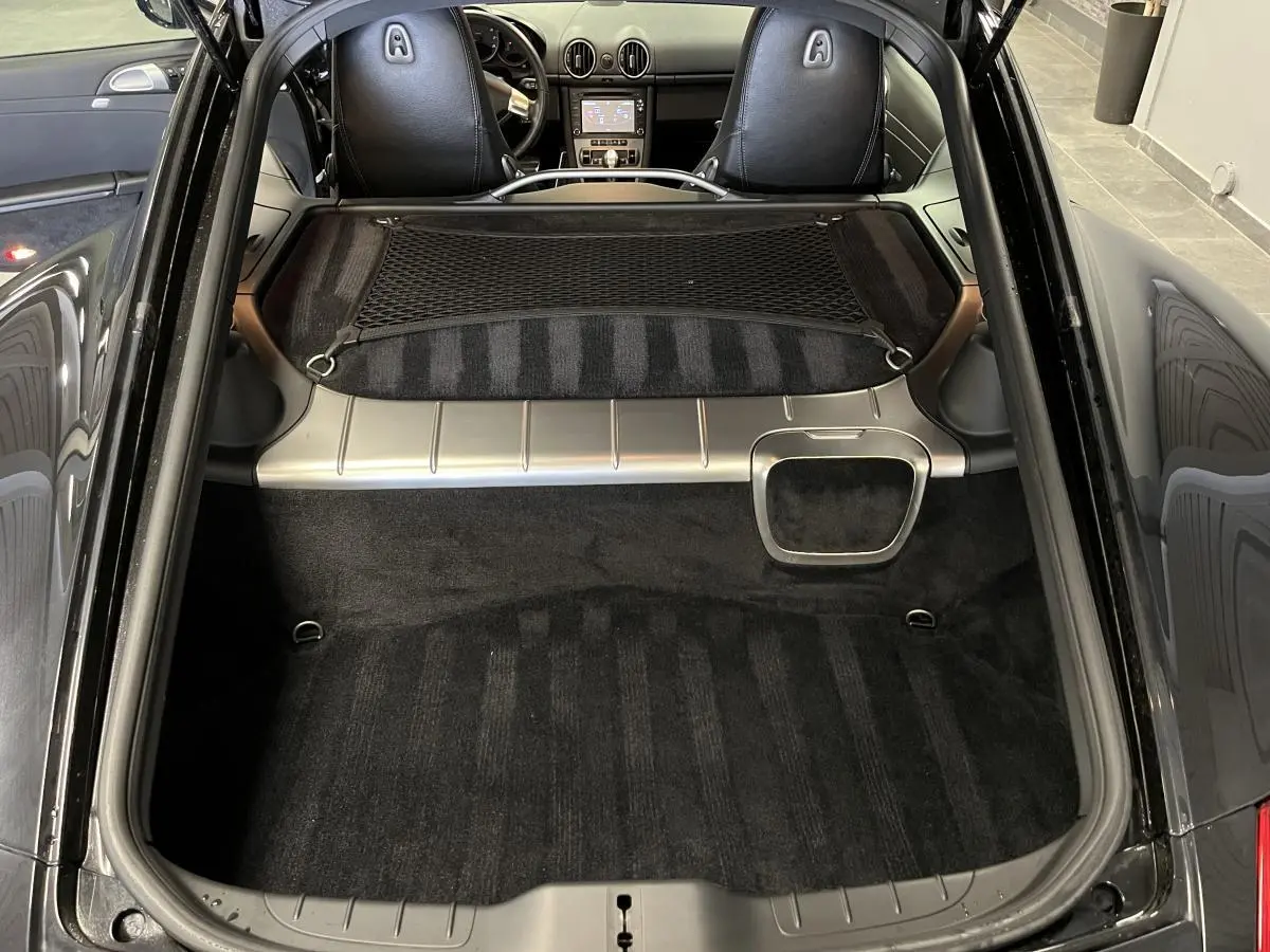 Vue arrière du coffre noir du Porsche Cayman 987 avec filet de rangement et intérieur cuir visible au loin
