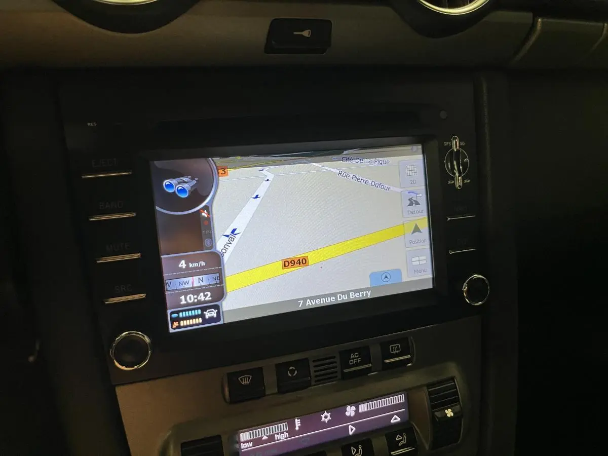 Écran de navigation PCM affichant une carte GPS dans le tableau de bord noir du Porsche Cayman 987 2008.