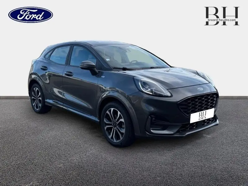 Ford Puma 1.0 EcoBoost gris métallisé en 3/4 avant droit, avec jantes alliage et calandre noire distinctive.