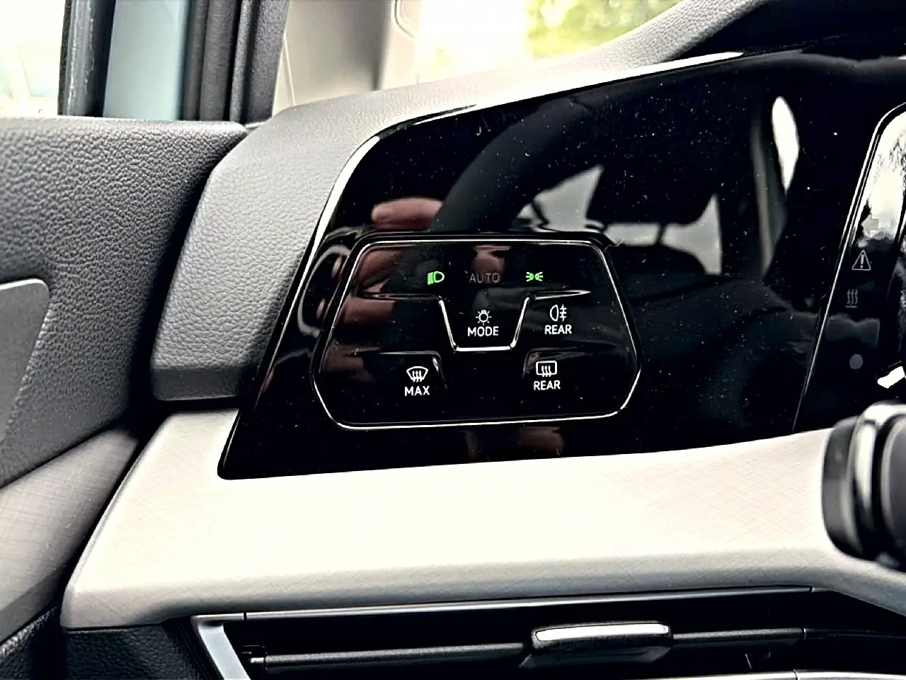 Gros plan sur les commandes d'éclairage et désembuage à gauche du tableau de bord de la Volkswagen Golf bleu glacier 2026.