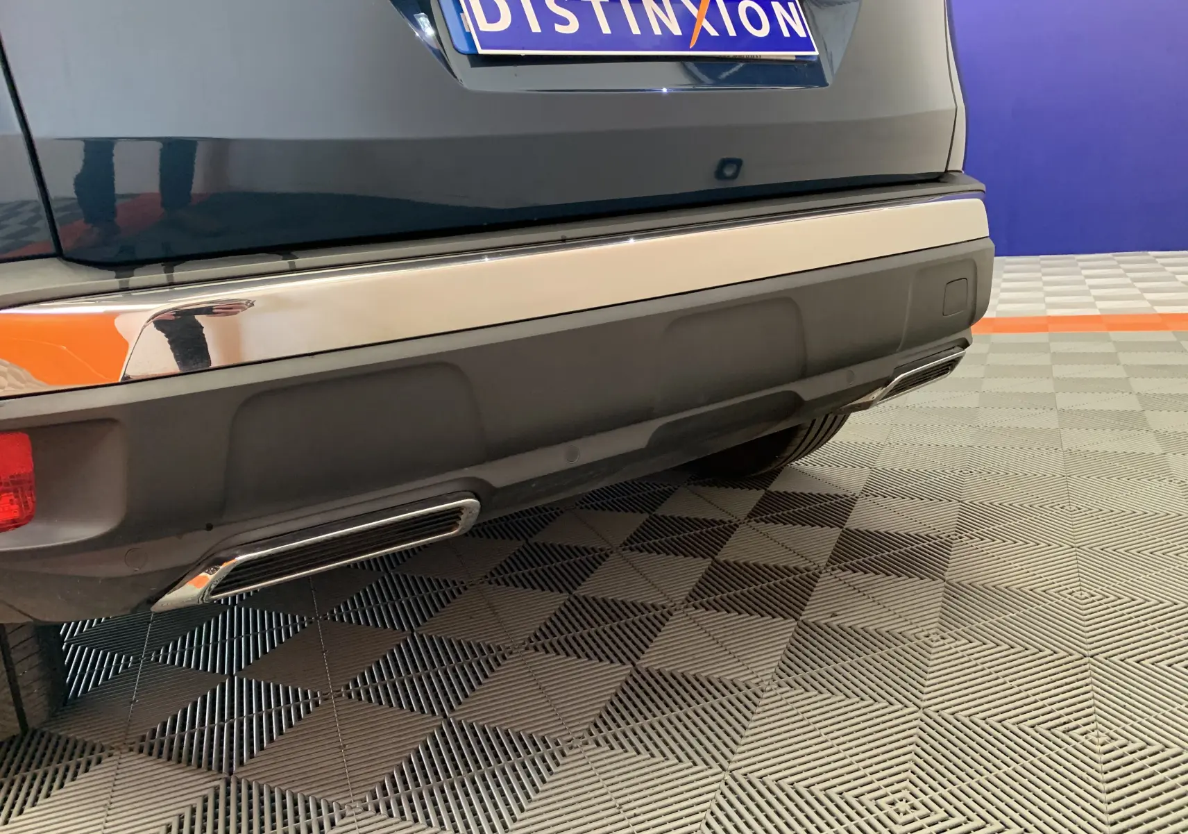 Gros plan sur le pare-chocs arrière bleu Célèbes du Peugeot 3008 avec sorties d'échappement chromées et plaque Distinxion.