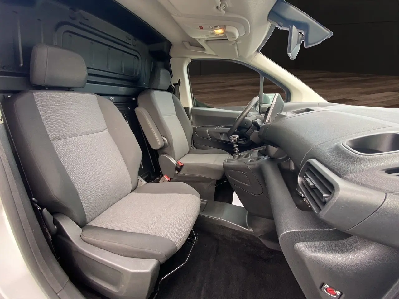 Vue intérieure côté conducteur du Citroën Berlingo 2019, sièges gris et tableau de bord noir avec levier de vitesses manuel.