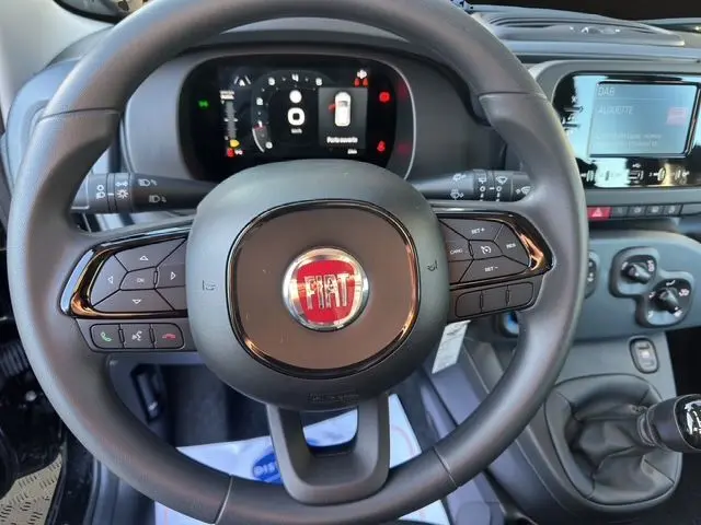 Vue rapprochée du volant noir de la Fiat Panda 2025 avec commandes intégrées et tableau de bord digital lumineux.