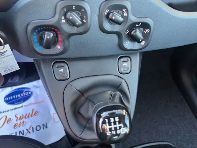 Gros plan sur la console centrale noire de la Fiat Panda 2025 montrant les commandes de climatisation et le levier de vitesse manuel.