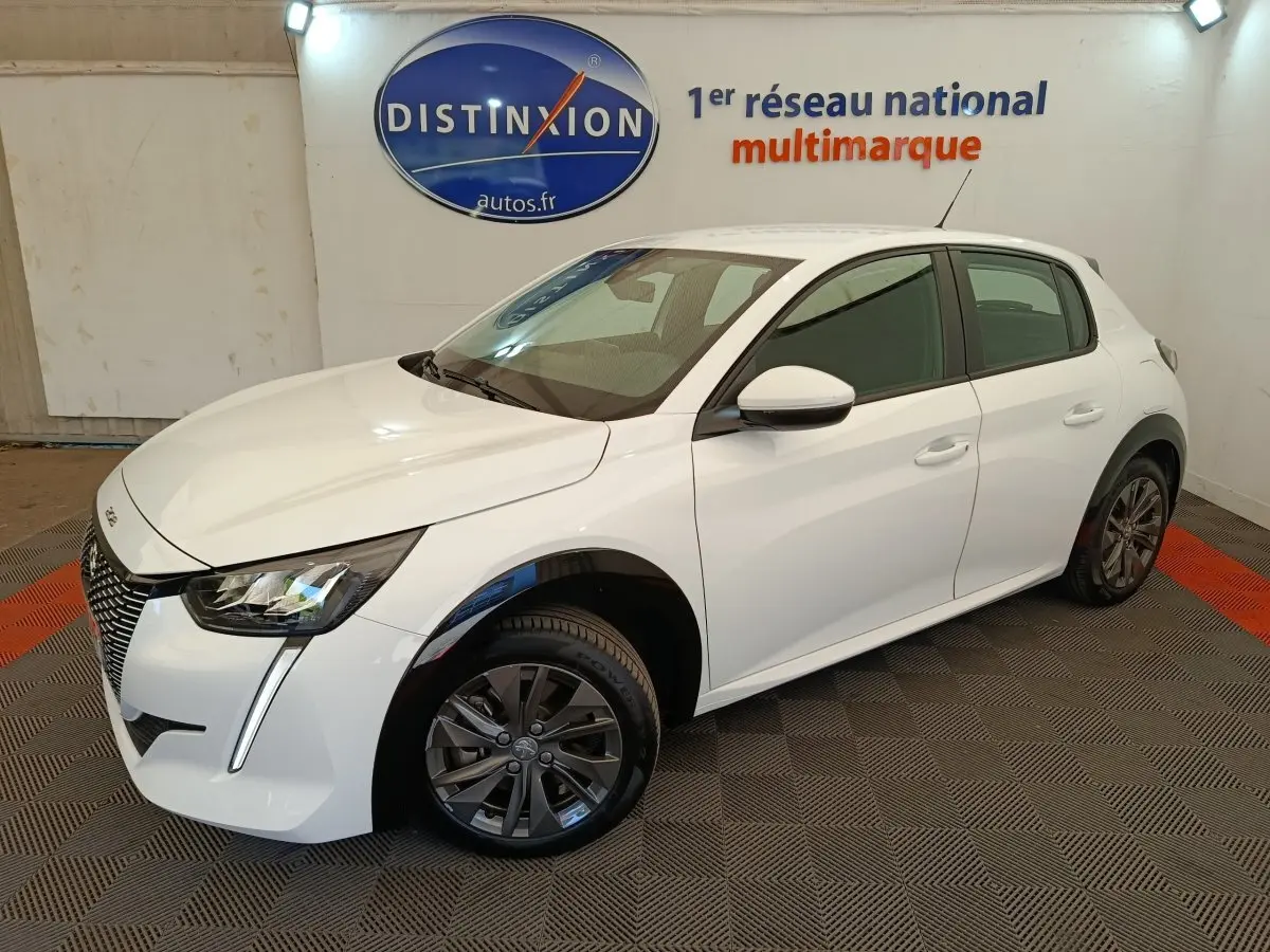 Peugeot 208 électrique blanche vue 3/4 avant droit, avec phares LED et jantes alliage gris foncé.