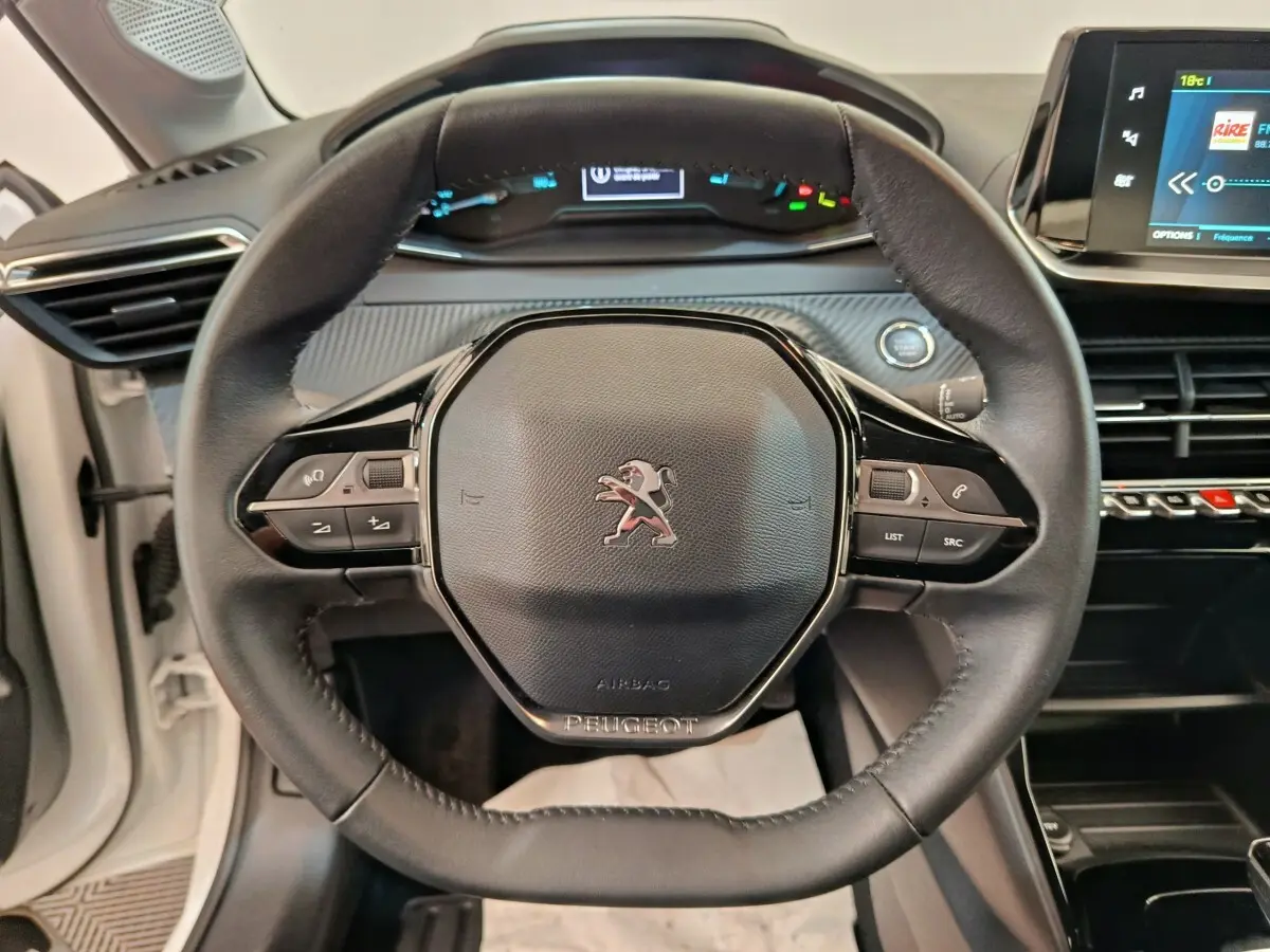 Vue rapprochée du volant cuir noir de la Peugeot 208 électrique Active Business R avec tableau de bord digital et écran tactile.