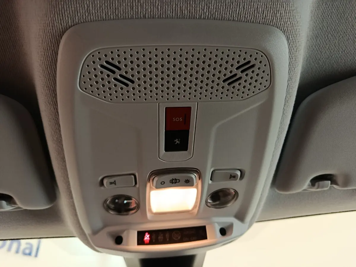 Vue intérieure du plafonnier blanc de la Peugeot 208 électrique 2021 avec éclairage et bouton SOS rouge allumé.