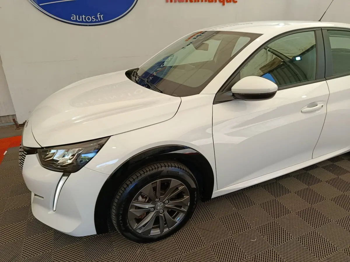 Peugeot 208 électrique blanche vue 3/4 avant droit, avec phares LED et jantes alliage foncé.