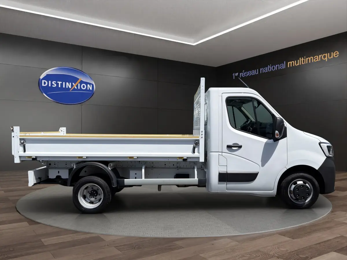 Profil droit d’un utilitaire Renault Master blanc avec benne, jantes acier et cabine simple, en showroom.