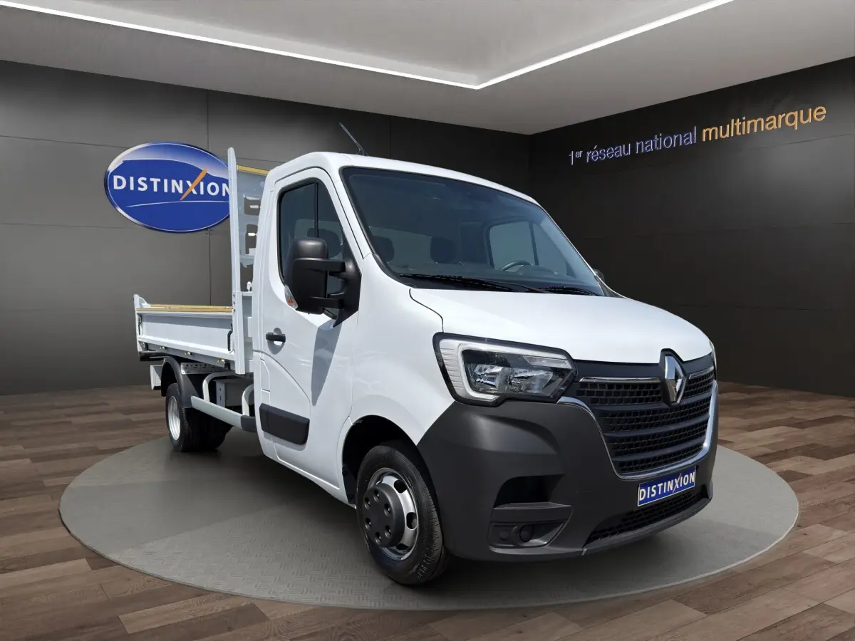 Renault Master blanc en 3/4 avant droit avec benne, calandre noire et jantes acier dans showroom.