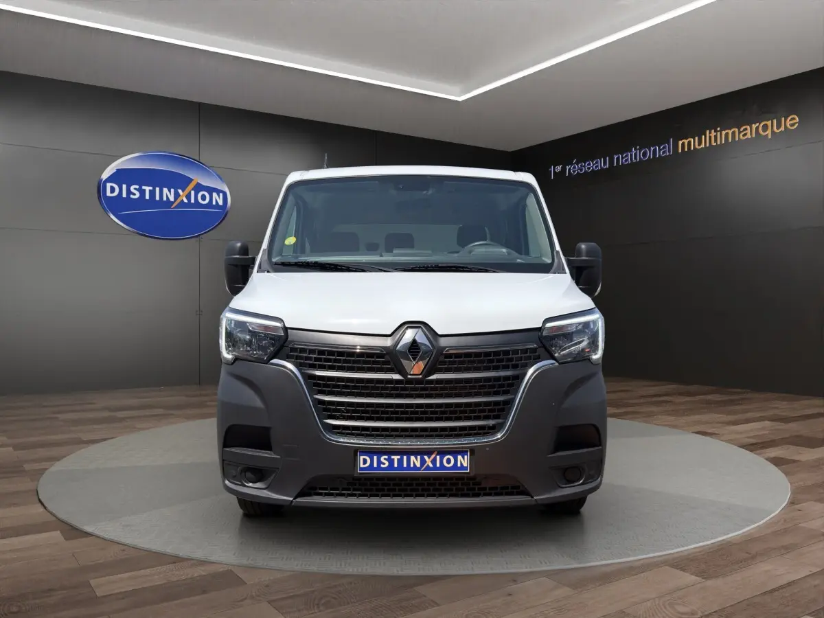 Renault Master blanc vu de face, avec calandre noire proéminente et phares modernes à LED dans un showroom.