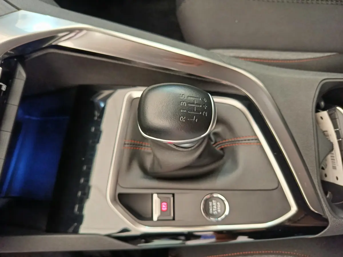 Gros plan sur le levier de vitesses manuel noir avec surpiqûres rouges dans le Peugeot 3008 gris foncé 2020.