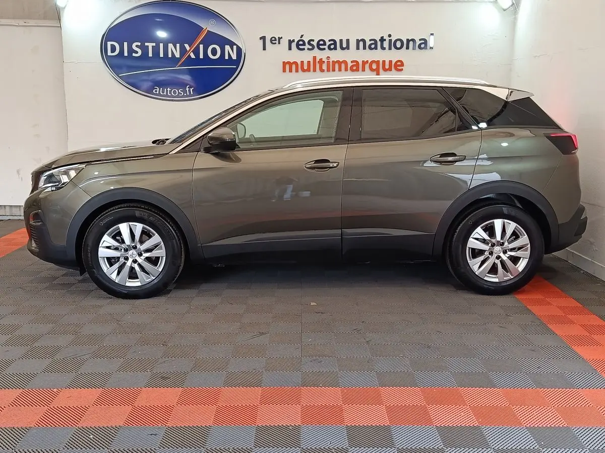 Profil côté gauche d'un Peugeot 3008 gris foncé de 2020 garé en intérieur avec jantes alliage et vitres teintées.