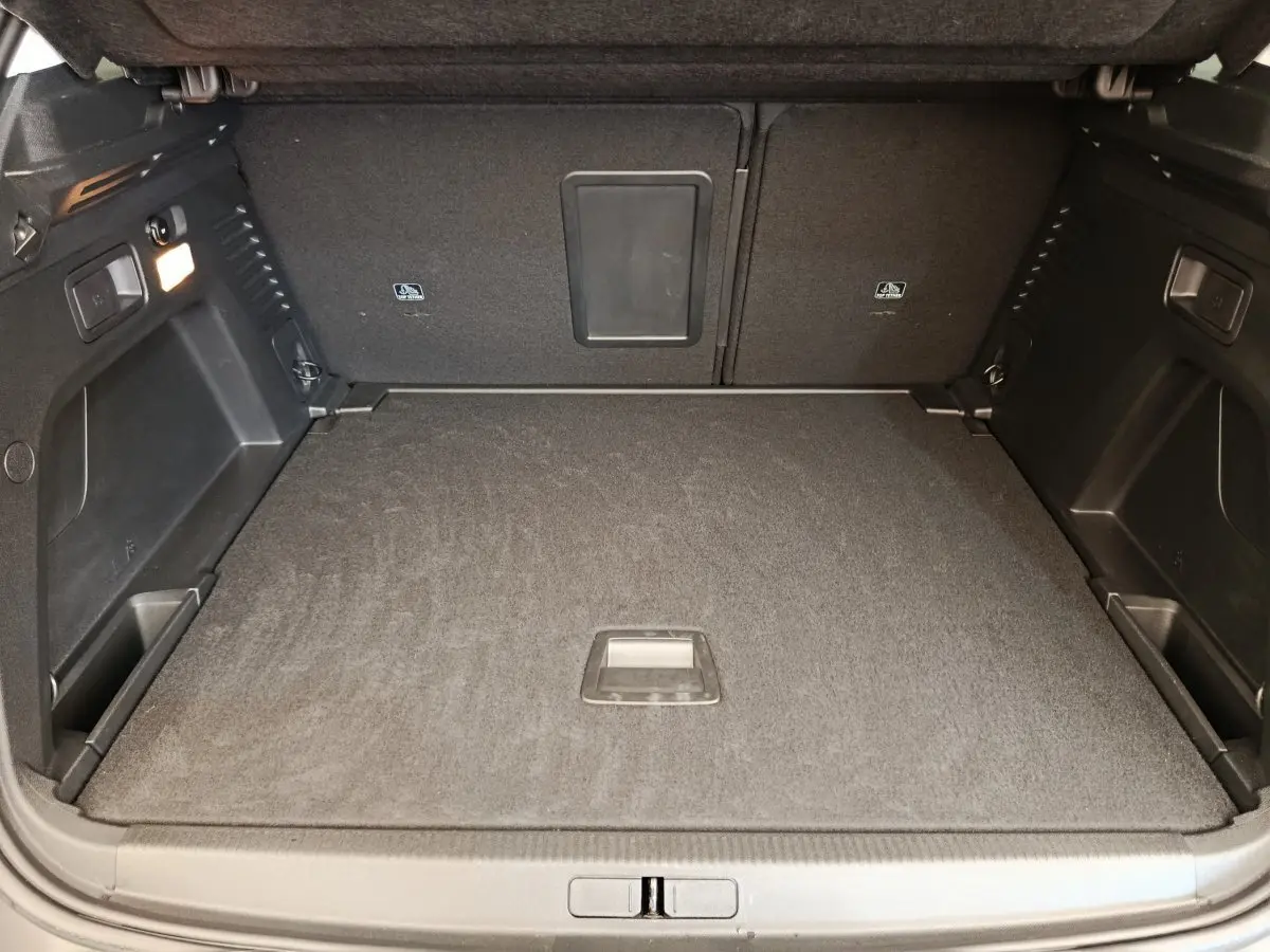 Coffre spacieux gris foncé du Peugeot 3008 Puretech 130 S&S vu de l'arrière avec plancher plat et rangements latéraux.