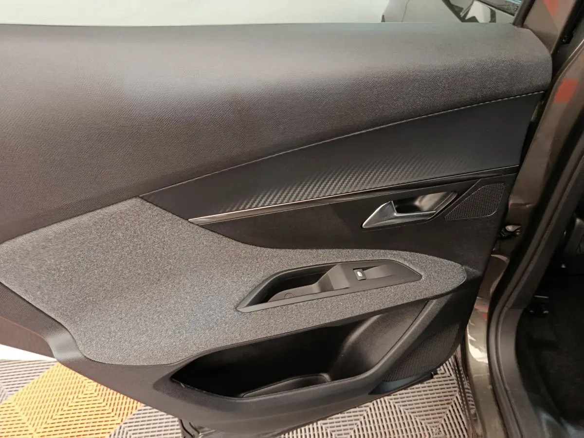 Gros plan sur la porte arrière droite grise du Peugeot 3008 2020, avec garniture tissu et insert effet carbone.