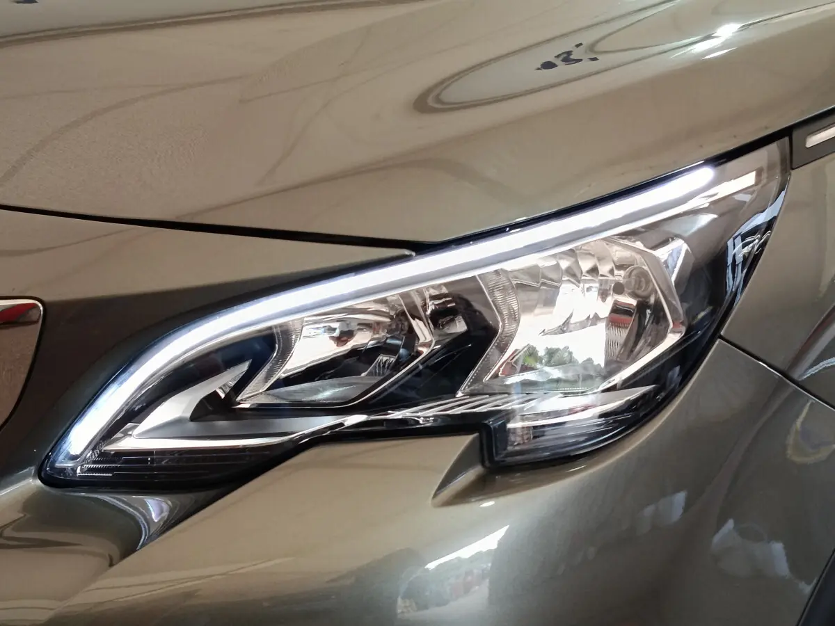 Gros plan sur le phare avant droit du Peugeot 3008 gris foncé, soulignant ses lignes modernes et LED intégrées.