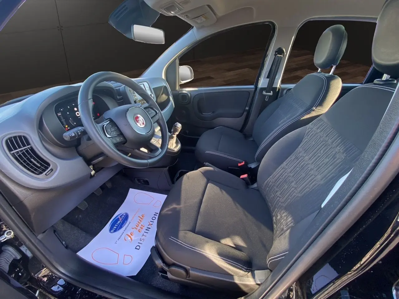 Intérieur avant droit de la Fiat Panda noire 2025, sièges tissu noir et tableau de bord avec écran multimédia.