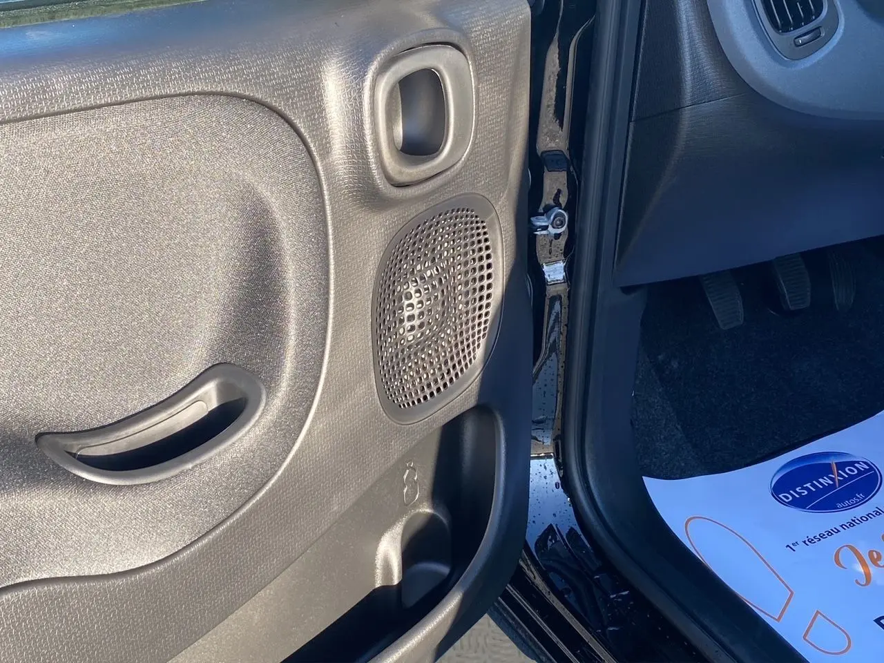 Gros plan sur la porte avant gauche noire de la Fiat Panda 2025, montrant le haut-parleur et la poignée intérieure.