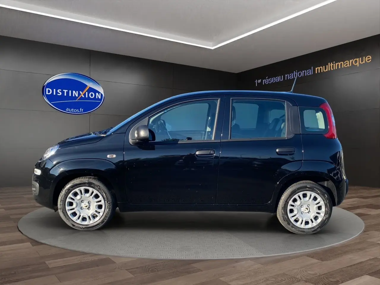 Profil côté gauche d'une Fiat Panda noire 2025, compacte et cinq portes, en présentation showroom intérieur.