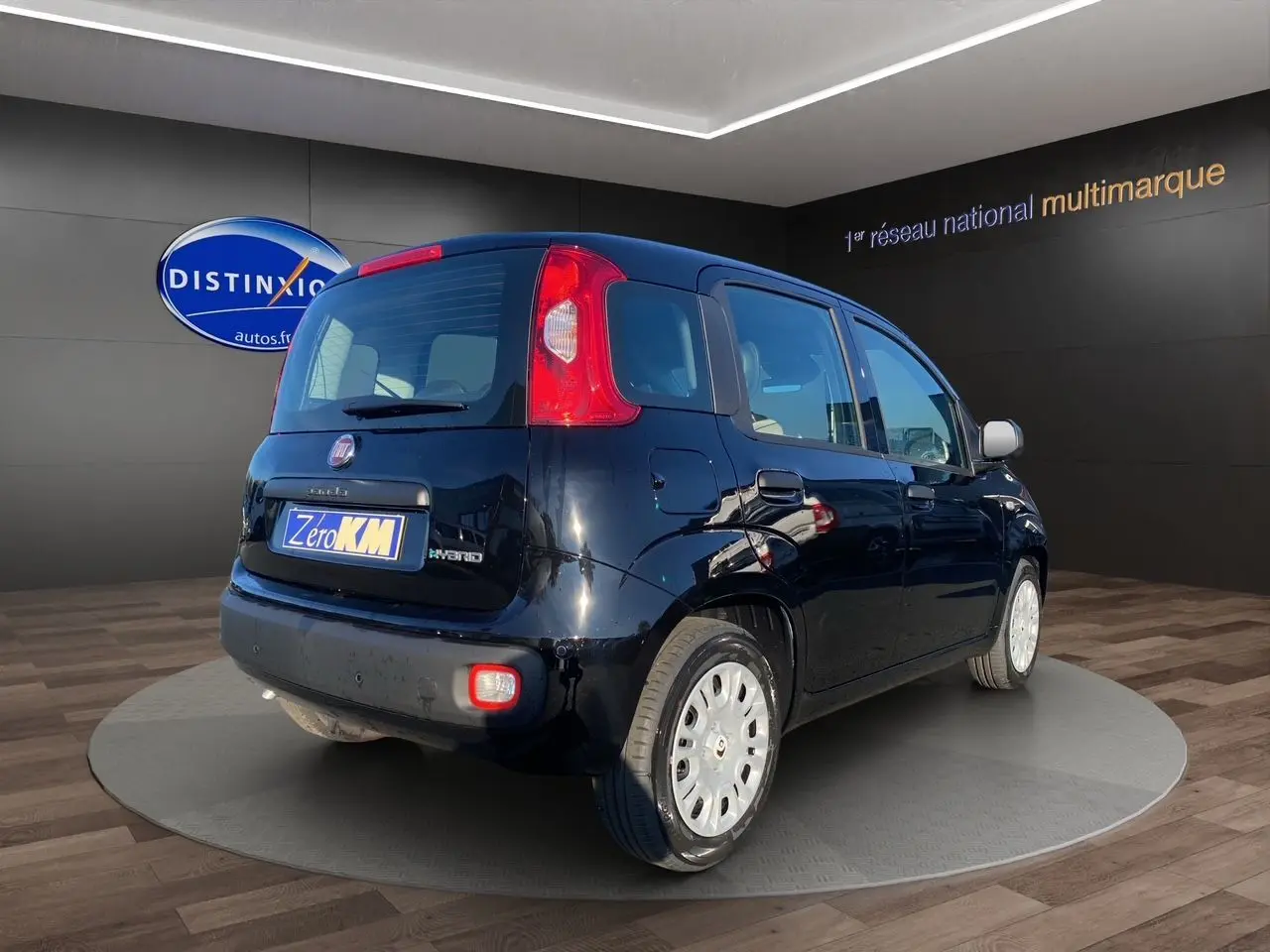 Vue 3/4 arrière droite d'une FIAT Panda noire 2025 avec hayon et feux arrière verticaux dans un showroom.