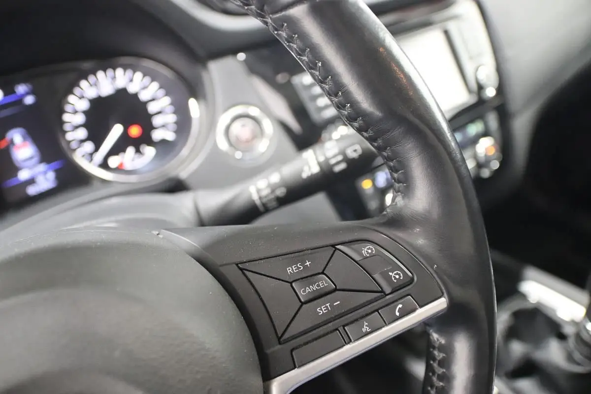 Gros plan sur le volant cuir noir du Nissan X-TRAIL 2021, montrant les commandes de régulateur de vitesse et téléphone.