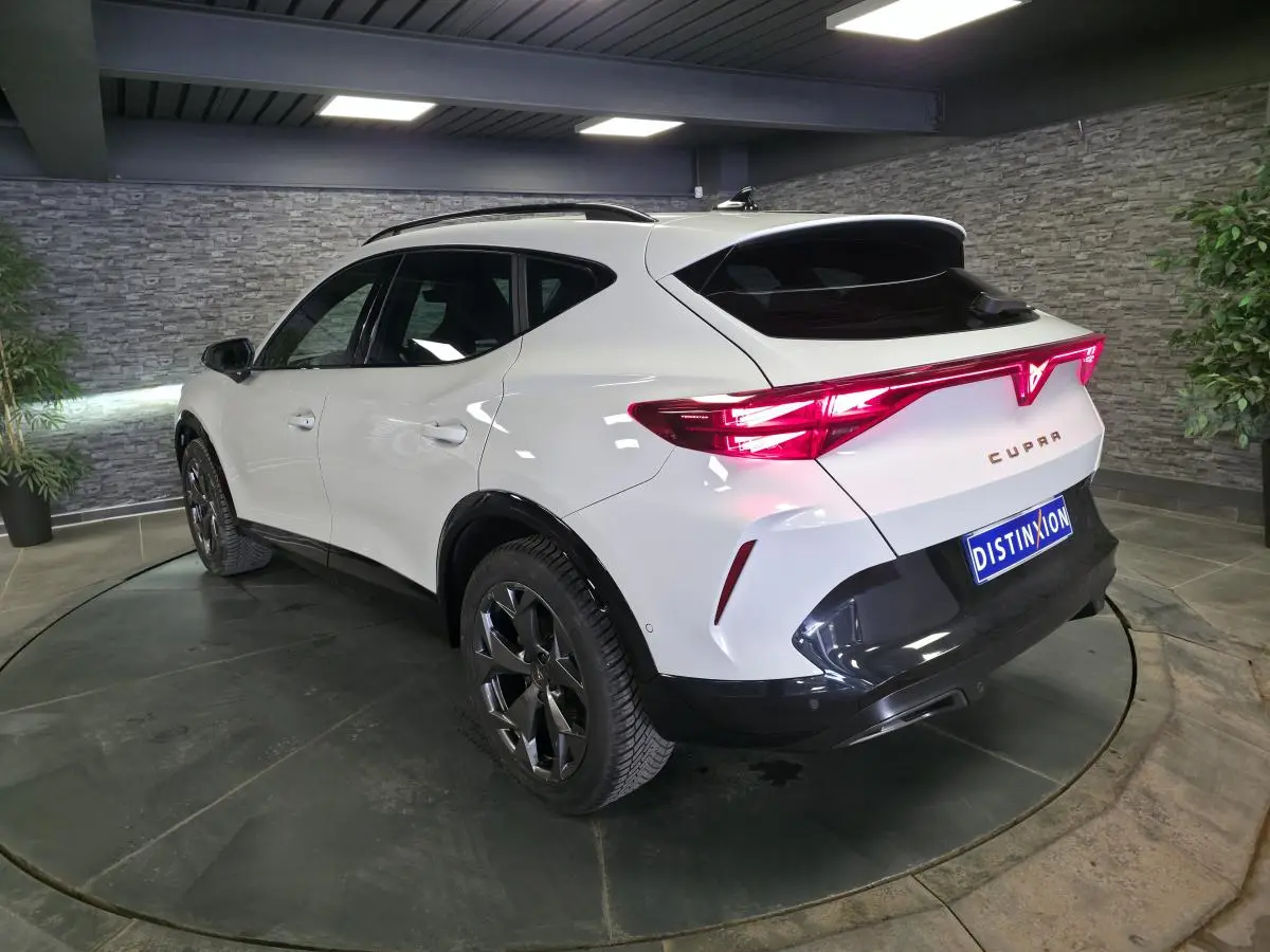 Vue 3/4 arrière droite du CUPRA Formentor blanc avec feux arrière en bandeau lumineux et jantes alliage noires.
