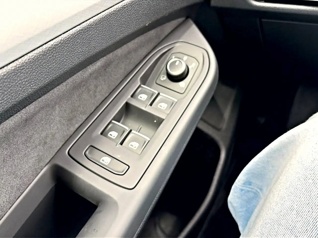 Gros plan sur la commande des vitres côté conducteur d’une Volkswagen Golf noire, intérieur tissu gris.
