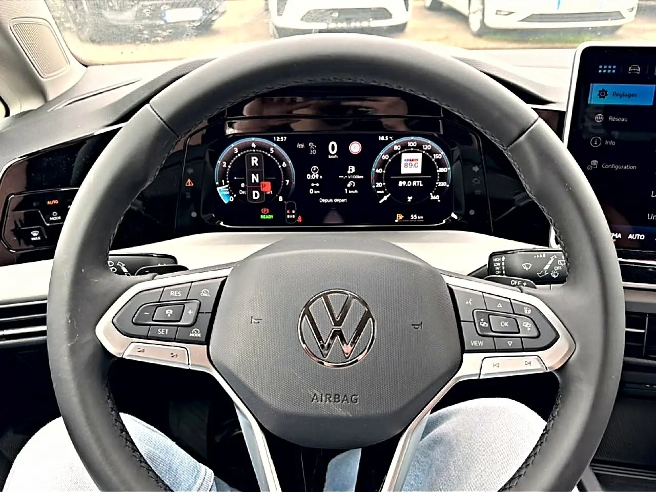 Vue rapprochée du volant noir de la Volkswagen Golf 2026 avec tableau de bord numérique et commandes intégrées.